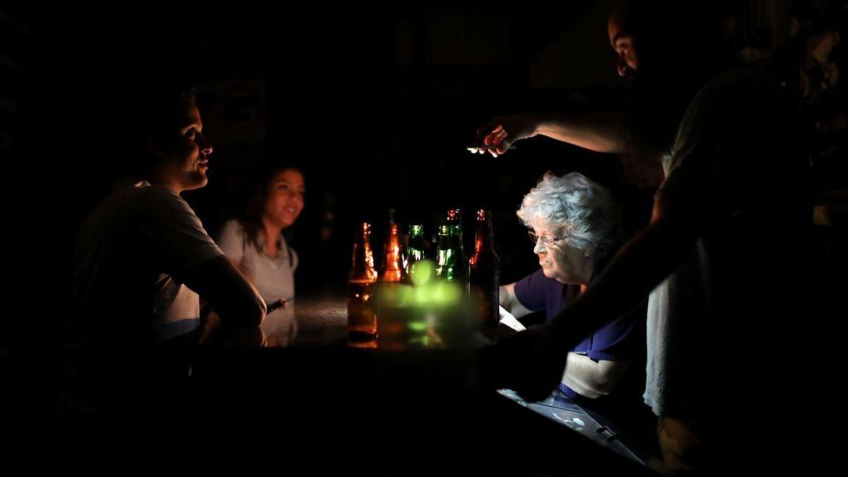 Personas en un bar en pleno apagón eléctrico en Venezuela.