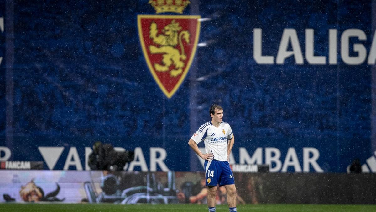 Francho, con los brazos en jarra, con el escudo del Real Zaragoza al fondo