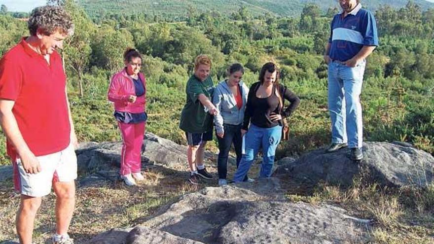 El vicepresidente de los comuneros, Antonio Graña (i.), ayer, observa un petroglifo en Amoedo.  // Faro