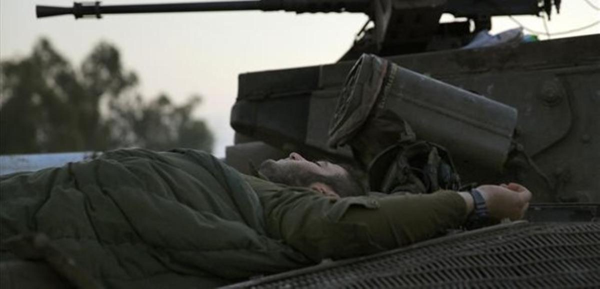Un soldat israelià dorm sobre un tanc al costat de la frontera amb Gaza.