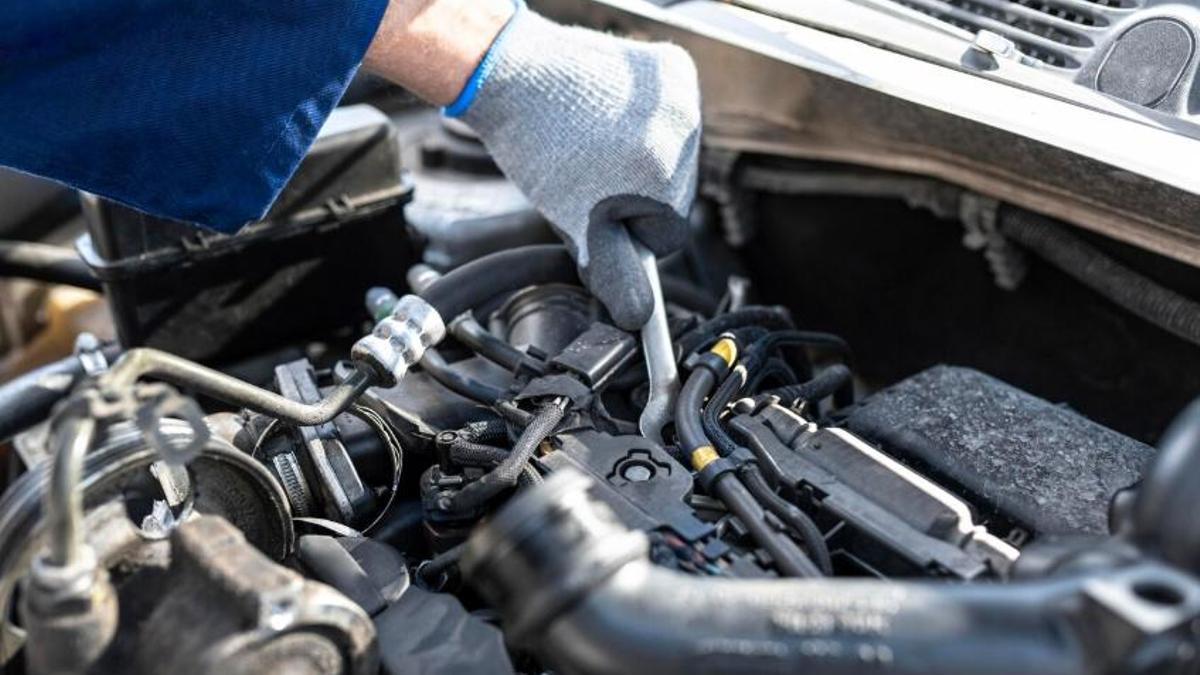 Un mecánico revisa el motor de un coche.