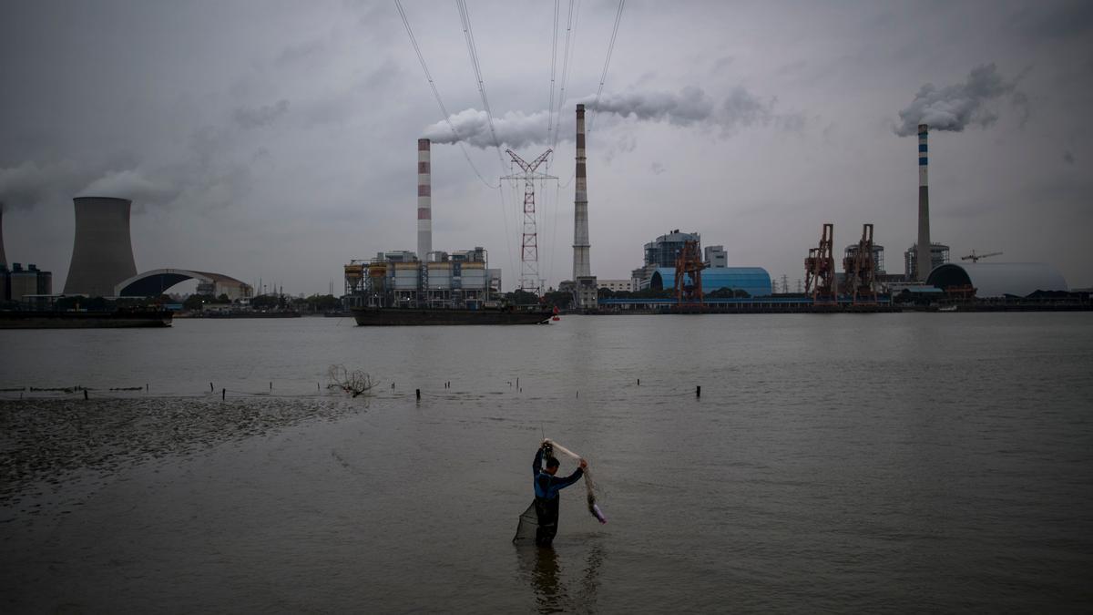 Un hombre pesca frente a una central eléctrica de carbón en Shanghái