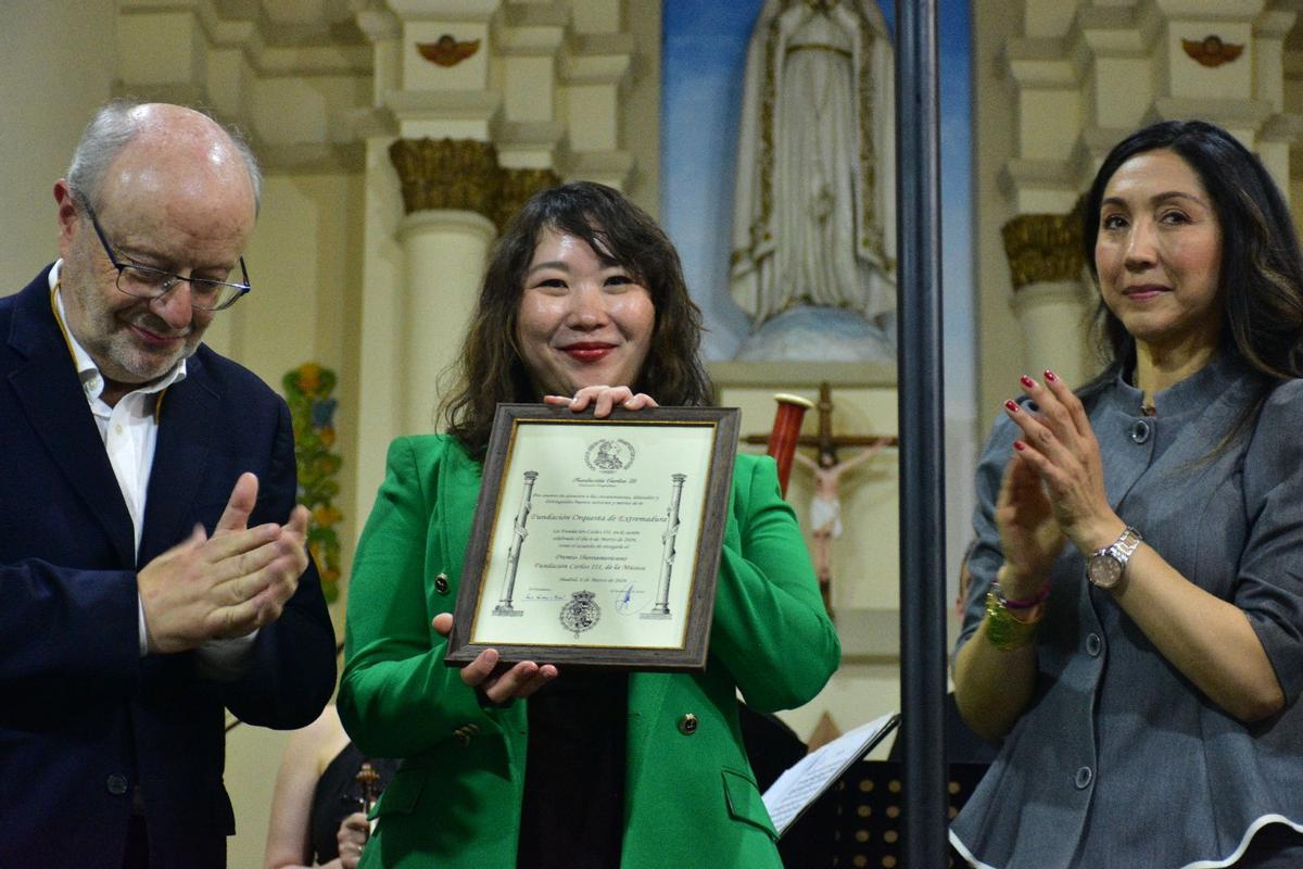 Hae Won Oh, gerente de la Fundación Orquesta de Extremadura, recibe el galardón de manos del presidente de la Fundación Carlos III, Carlos Escudero De Burón, y la vicepresidenta de la misma entidad, Vanessa Pereira.