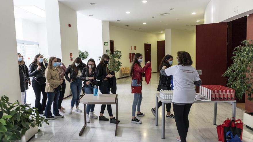 Alumnos universitarios pasan el protocolo de limpieza antes de entrar al salón de actos.