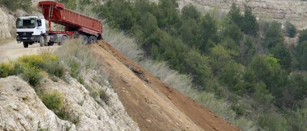 Un camión aboca tierra en la cantera de Llaurí para ataludar parte de la montaña, donde después se plantarán pinos.