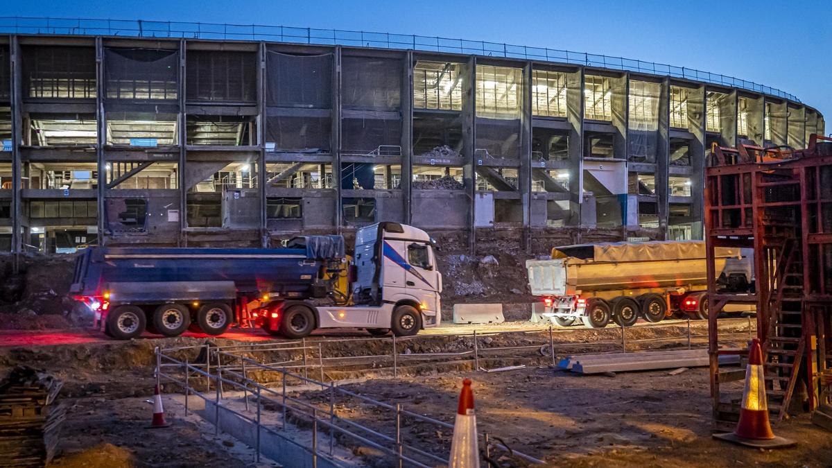 Camiones dentro del recinto en obras del Camp Nou, en Barcelona, al amanecer.