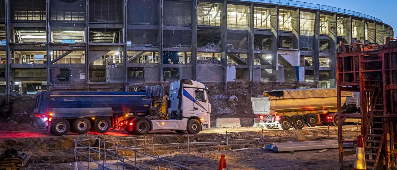 Camiones dentro del recinto en obras del Camp Nou, en Barcelona, al amanecer.