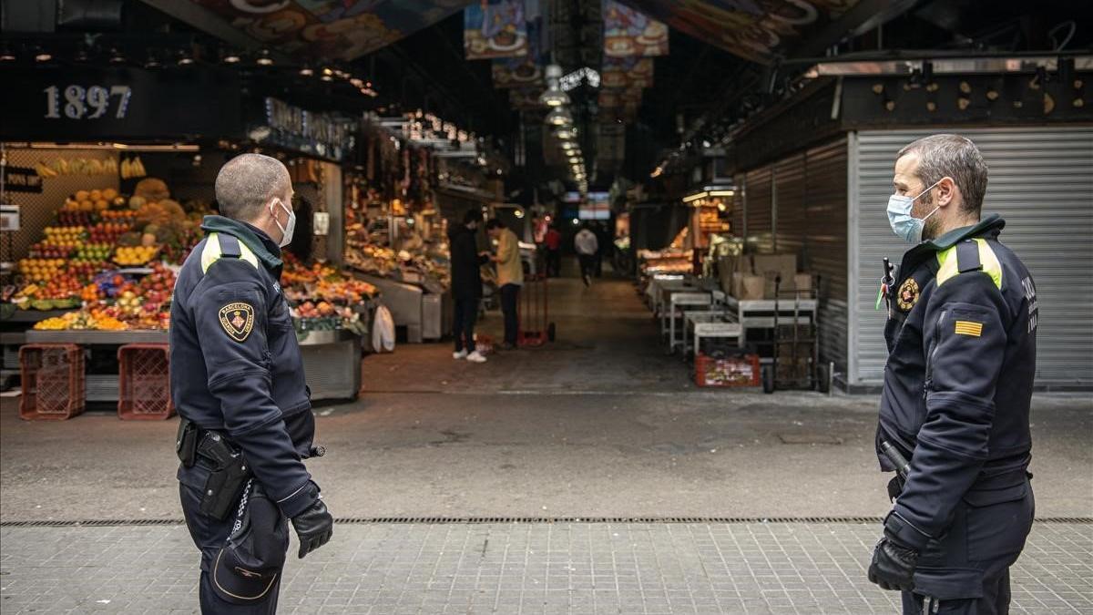 Agentes de la Guardia Urbana controlando el acceso a la Boqueria, con un 75% de puestos cerrados.