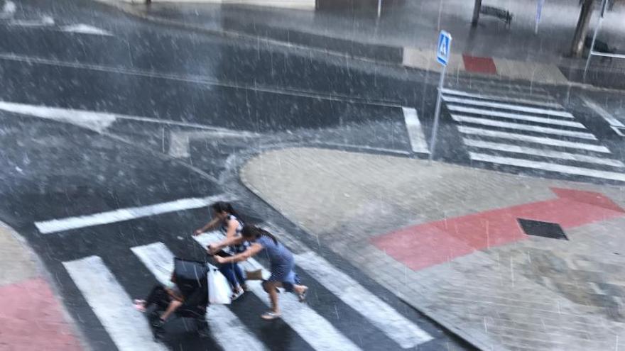 Corriendo bajo la lluvia en Elda tras verse sorprendidas por la tormenta en el mercadillo de Santa Bárbara