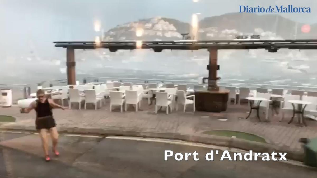 Una mujer huye del temporal en el Port d'Andratx mientras vuelan sillas y contenedores