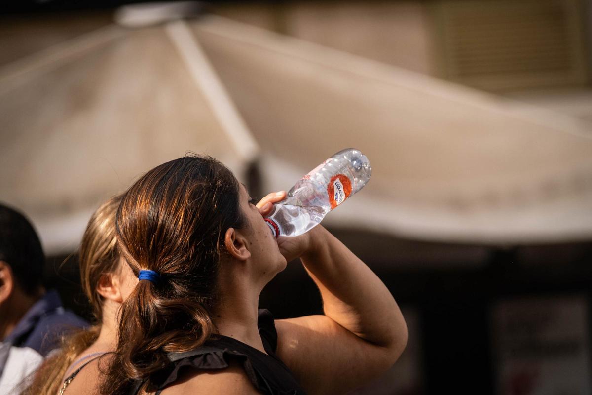 Una mujer toma agua para refrescarse y mitigar el calor durante la ola de calor de octubre en Canarias.