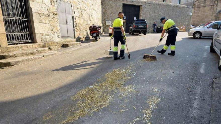 Unos operarios del servicio de limpieza retiran con escoba y recogedor los residuos de ganadería en el entorno de la plaza de toros. // G.S.