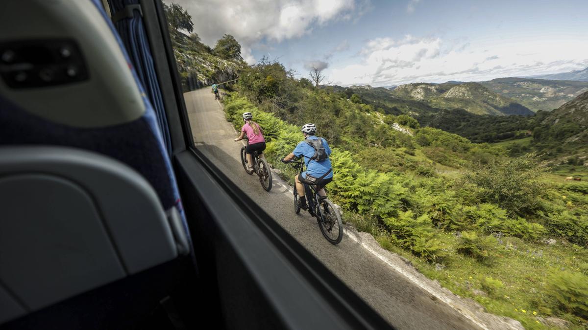 Un autobús del plan de transporte adelanta a dos cicloturistas.