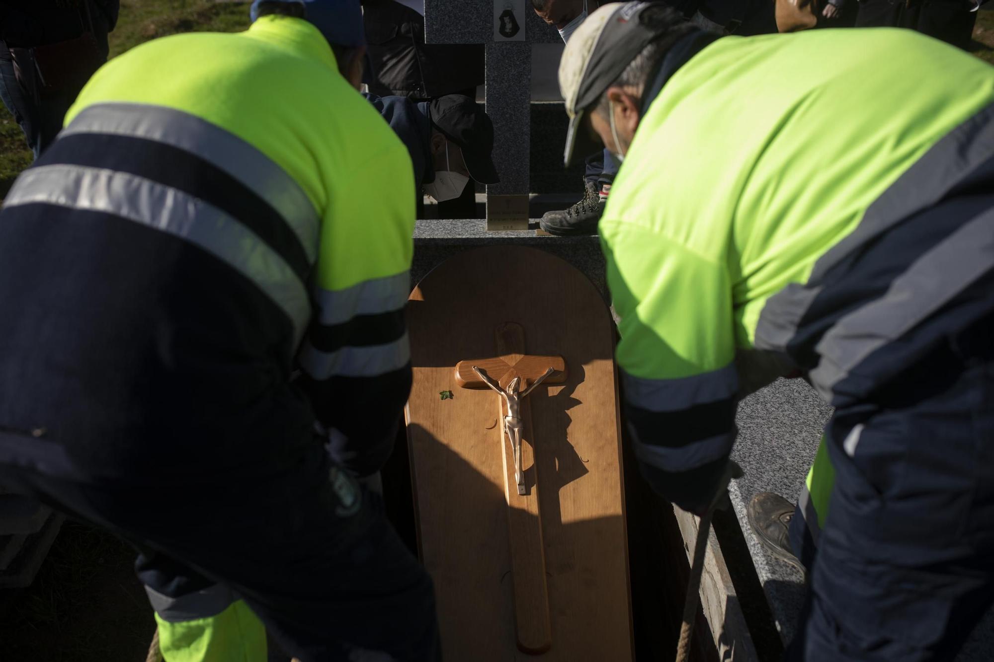 Trabajadores del cementerio introducen un ataúd en una sepultura