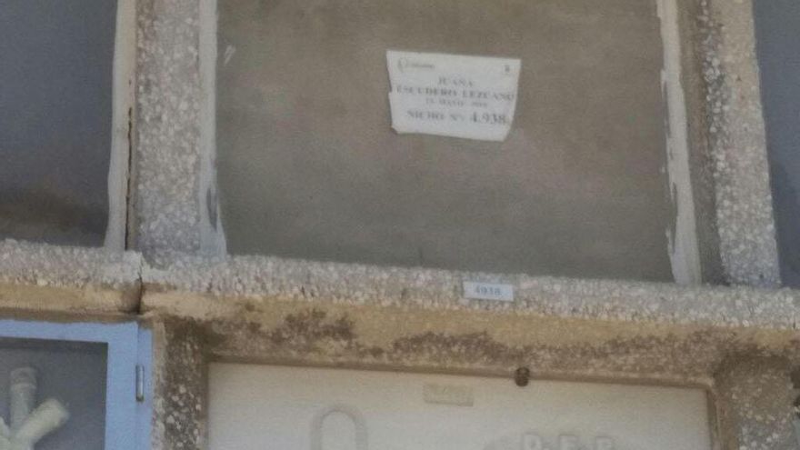 Fotografía cedida por Juana Escudero Lezcano y realizada en el cementerio Parcemasa San Gabriel de Málaga, en la que aparece ella misma delante del nicho (arriba sin lápida) en el que están escritos en un papel todos los datos de la mujer que se supone está enterrada allí y que coinciden exactamente con los de ella.