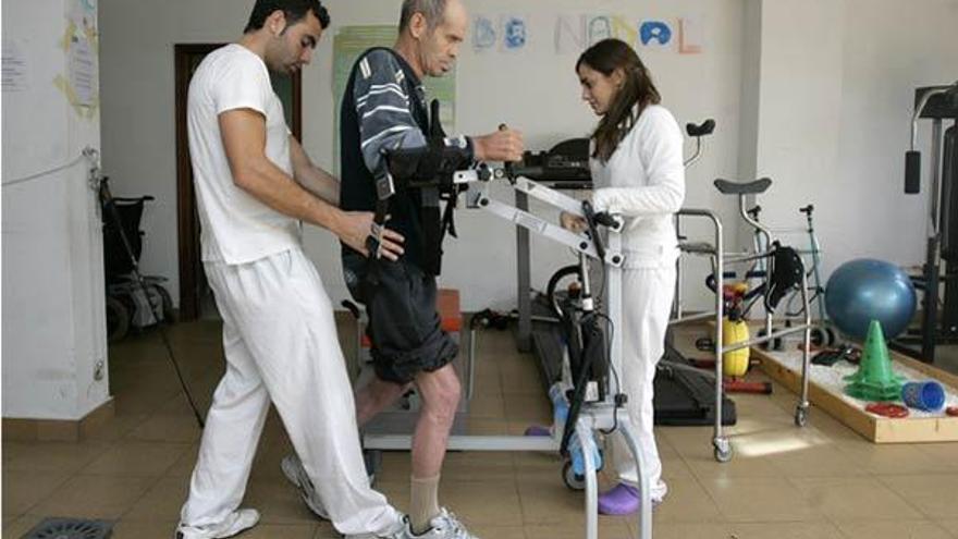 Fisioterapeutas ayudan a un pacientes a caminar.  //  Xoan Álvarez