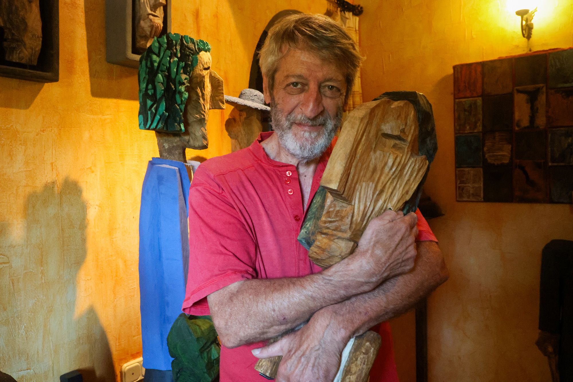 Tino Canicoba abraza una de sus esculturas de madera