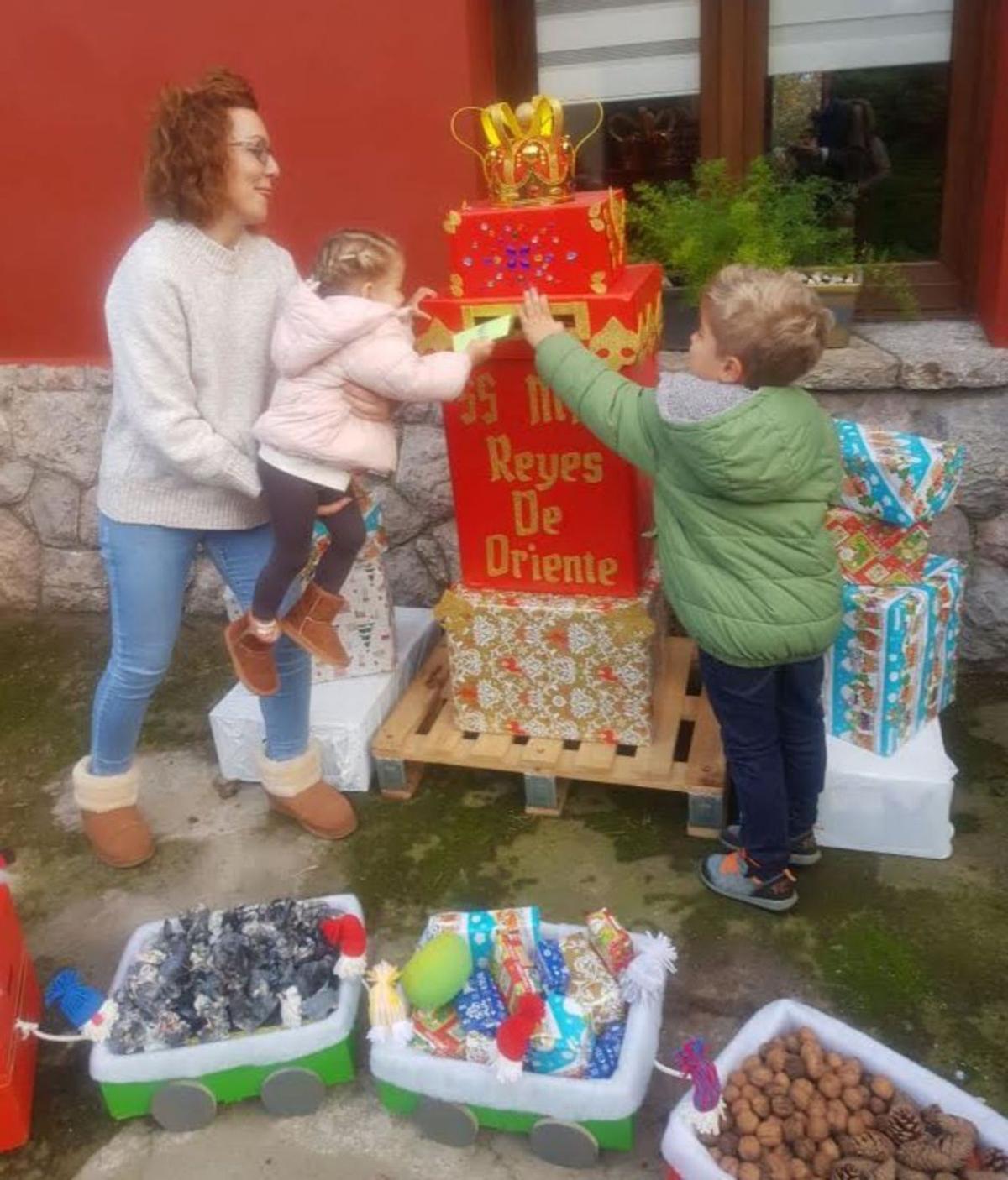 Laura Cruzado, con Noa y Naël Mondelo, echando en el buzón sus cartas para los Reyes Magos. | Vicente Alonso