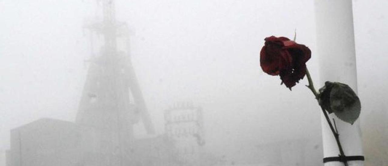 Una rosa recuerda a las víctimas del accidente del pozo Emilio del Valle, al fondo entre la niebla.