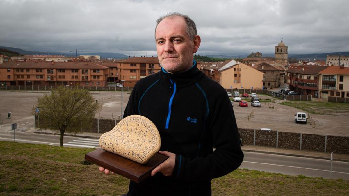 Francisco Gutiérrez, presidente de Arco, posa con la maqueta de la escultura prevista para homenajear a los trabajadores de la galletas de Aguilar, con los terrenos donde estaba la fábrica de Fontaneda, al fondo.