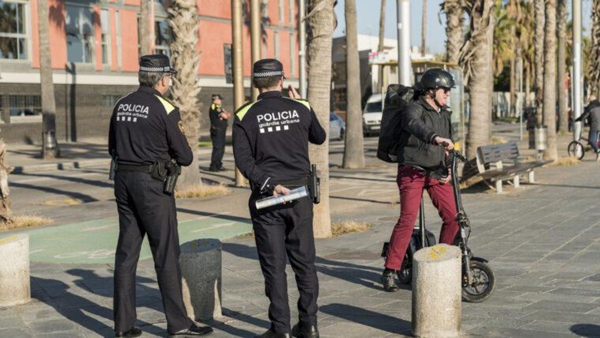 Dos agents de la Guàrdia Urbana, al costat dun home en patinet elèctric Dos agents de la Guàrdia Urbana, al costat dun home en patinet elèctric