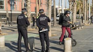 Dos agents de la Guàrdia Urbana, al costat dun home en patinet elèctric
