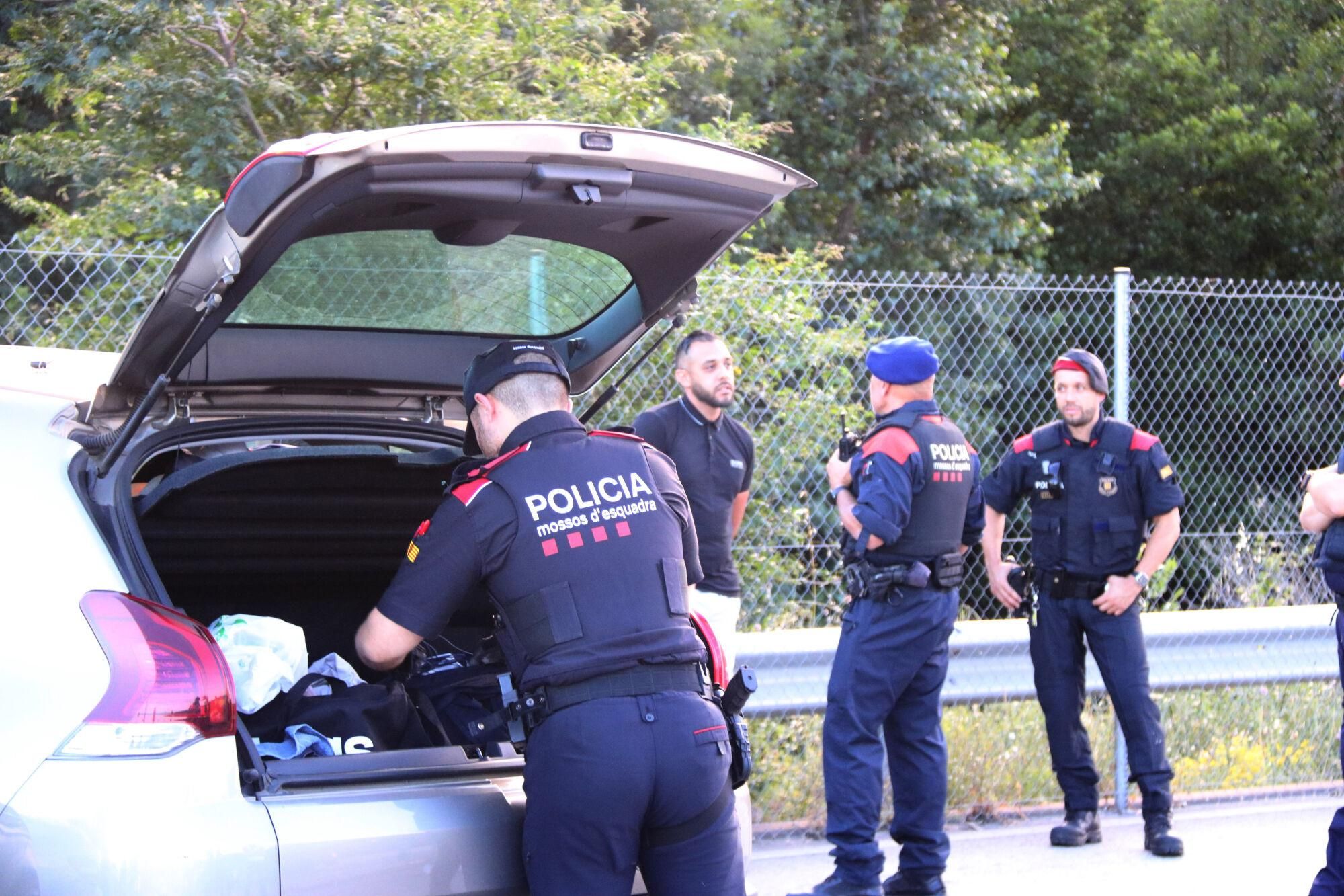 Un mosso registra el vehicle d'un home, mentre un altre agent el vigila