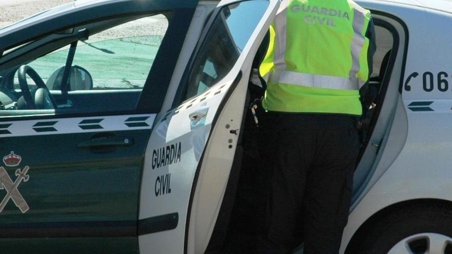 Un agente de la Guardia Civil junto a su vehículo.