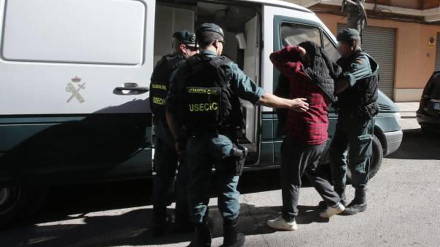 La Guardia Civil se lleva a uno de los detenidos en Alzira tras concluir el registro.