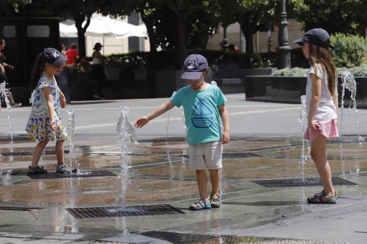 Unos niños se refrescan en la fuente de Las Tendillas.