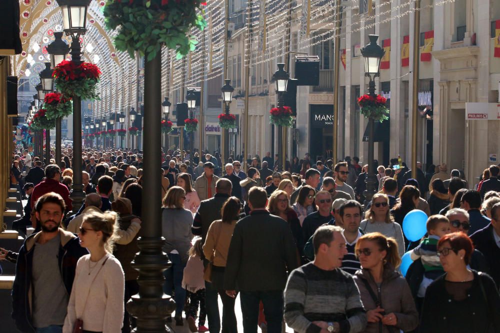 Muchos malagueños y turistas aprovechan el buen tiempo y el día festivo por la Inmaculada Concepción para pasear y realizar las compras navideñas en el Centro de Málaga.