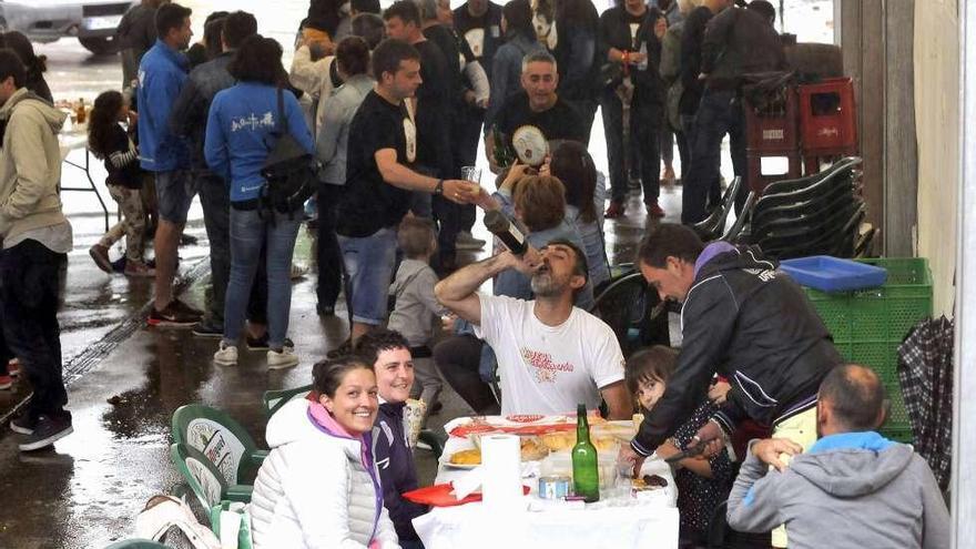 Grupos de personas meriendan y disfrutan en la carpa de la jira en Blimea. A la derecha, un camarero escancia sidra en la romería de Lada.