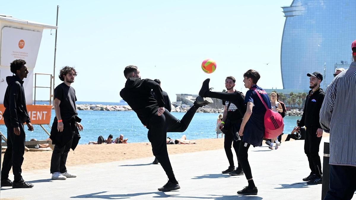 Aficionados del PSG juegan con una pelota en la Barceloneta