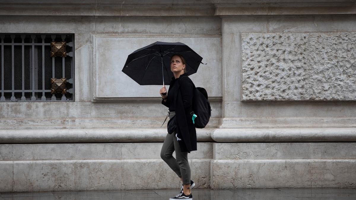 Una mujer se protege de la lluvia bajo su paraguas