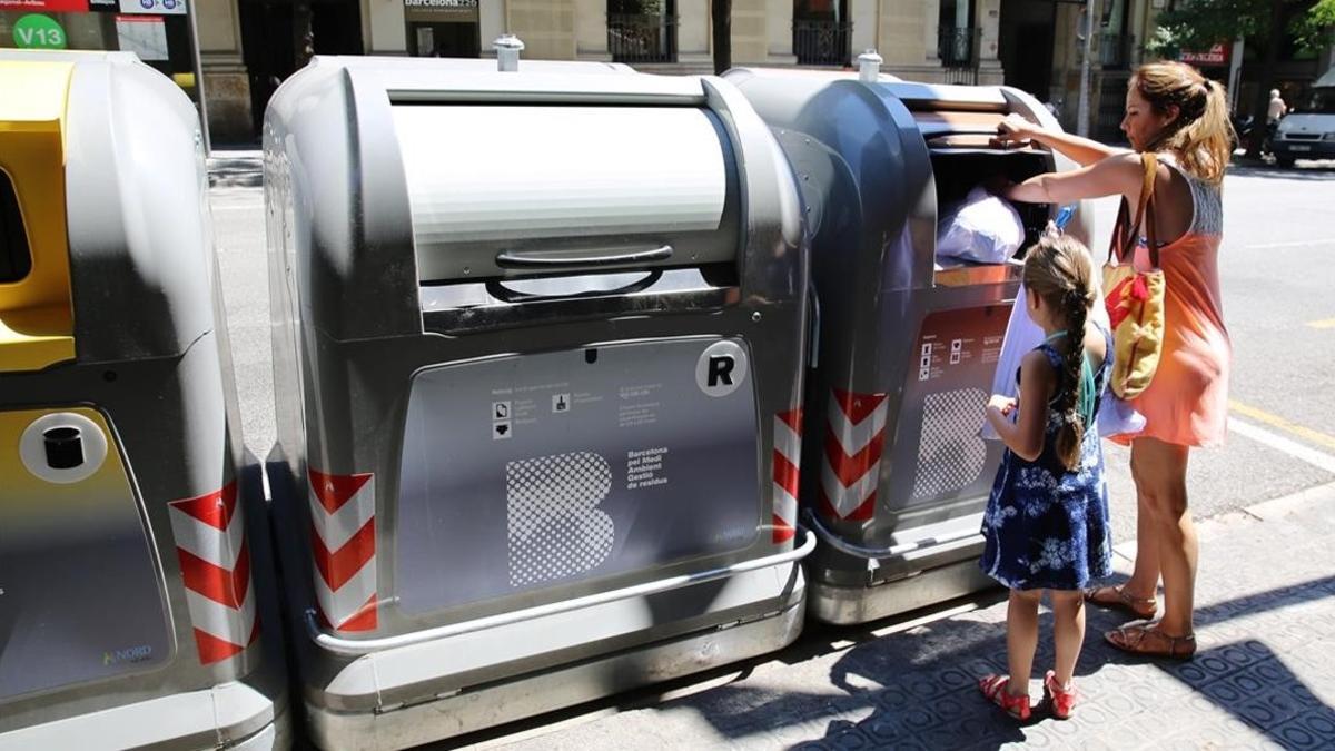 Una mujer tira una bolsa al contenedor de la basura orgánica en Barcelona.