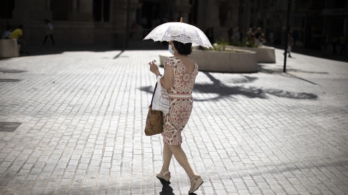 Una mujer se protege este martes del intenso calor en una calle del centro histórico de Valencia.