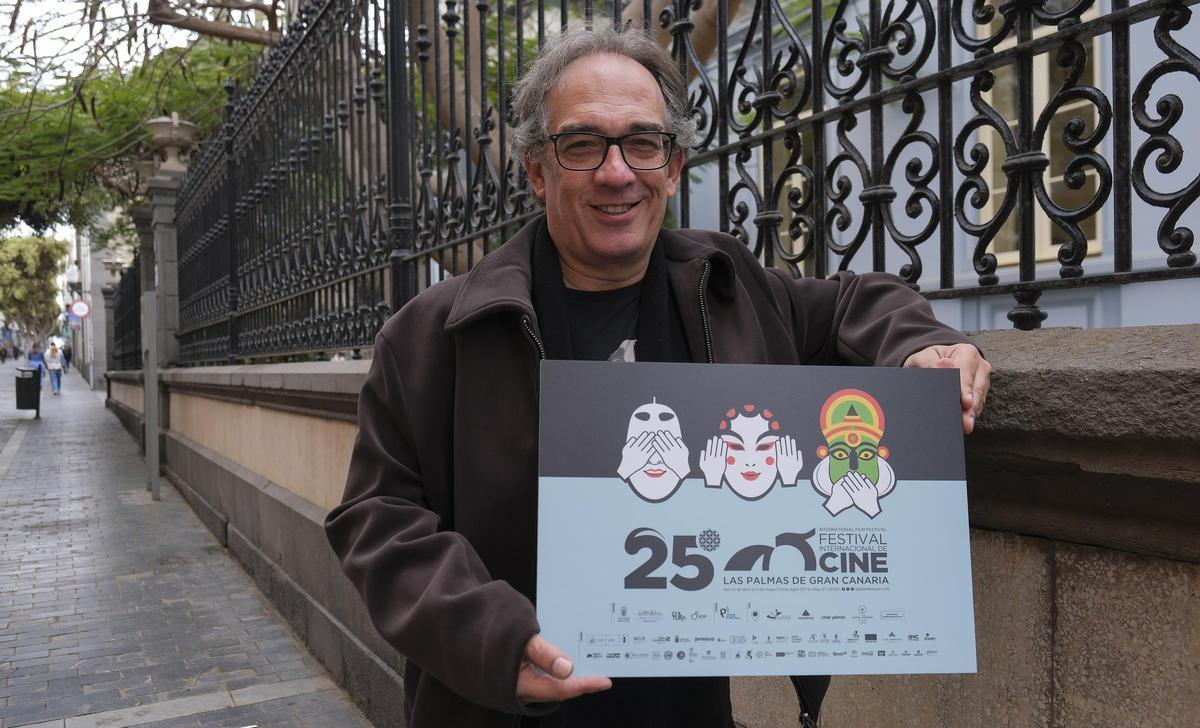 Luis Miranda, junto al edificio Quegles, con el cartel del 25º Festival de Cine de Las Palmas de Gran Canaria con los tres caretas que definen una buena parte de la programación de este año.