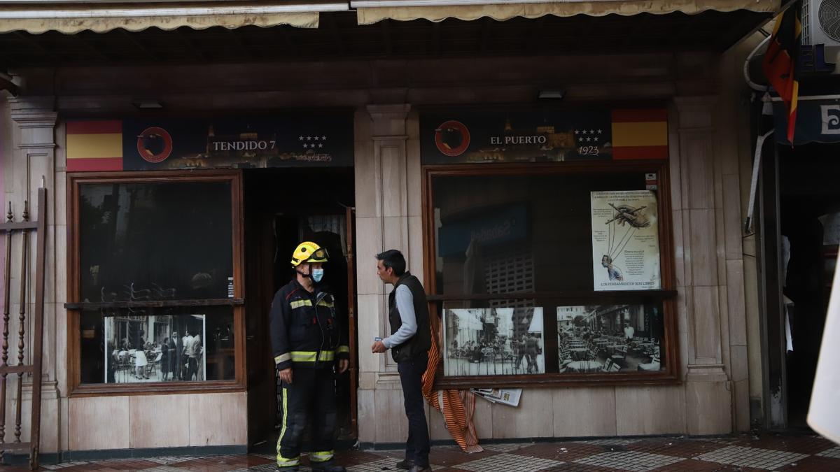 Un bombero habla con un hombre a las puertas del bar donde se ha registrado el incendio.
