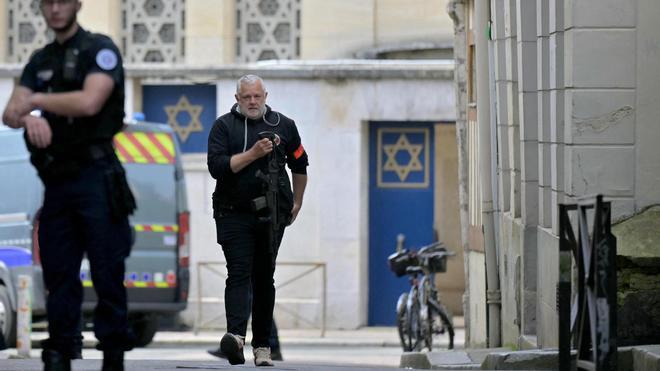 17 May 2024, France, Rouen: A policeman holds a rifle as he walks past the entrance of a synagogue where French police killed an armed man who had tried to set the fire on the building. Photo: Lou Benoist/AFP/dpa