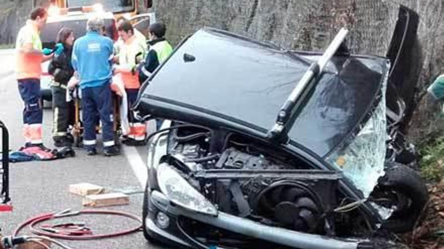 El estado en el que quedó uno de los coches, con el herido grave, atendido por los sanitarios, detrás.