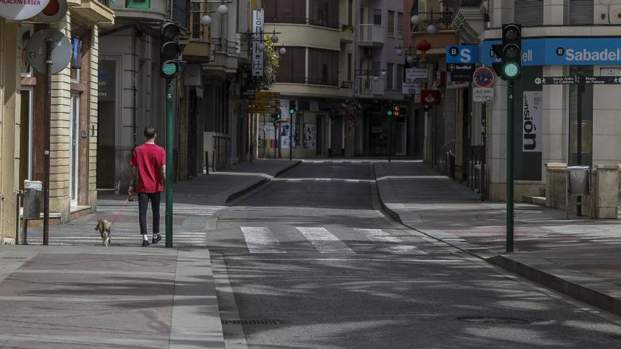 Una ciudadano de Elche pasea con su perro en una calle vacía de Elche.