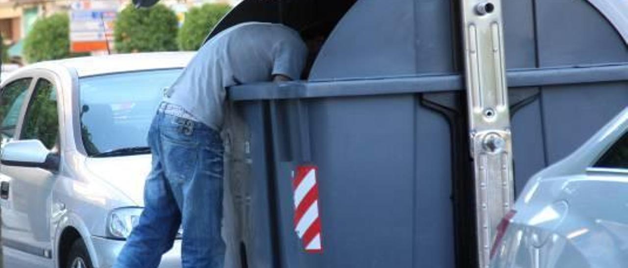 Foto de archivo en la que un joven rebusca entre la basura en un contenedor de Alzira.