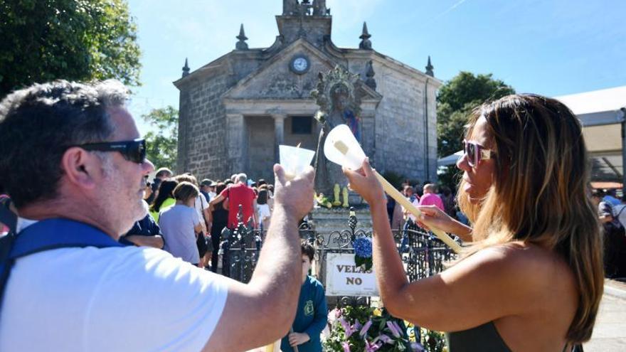 Encendido de velas ante la imagen de piedra de la Virgen.