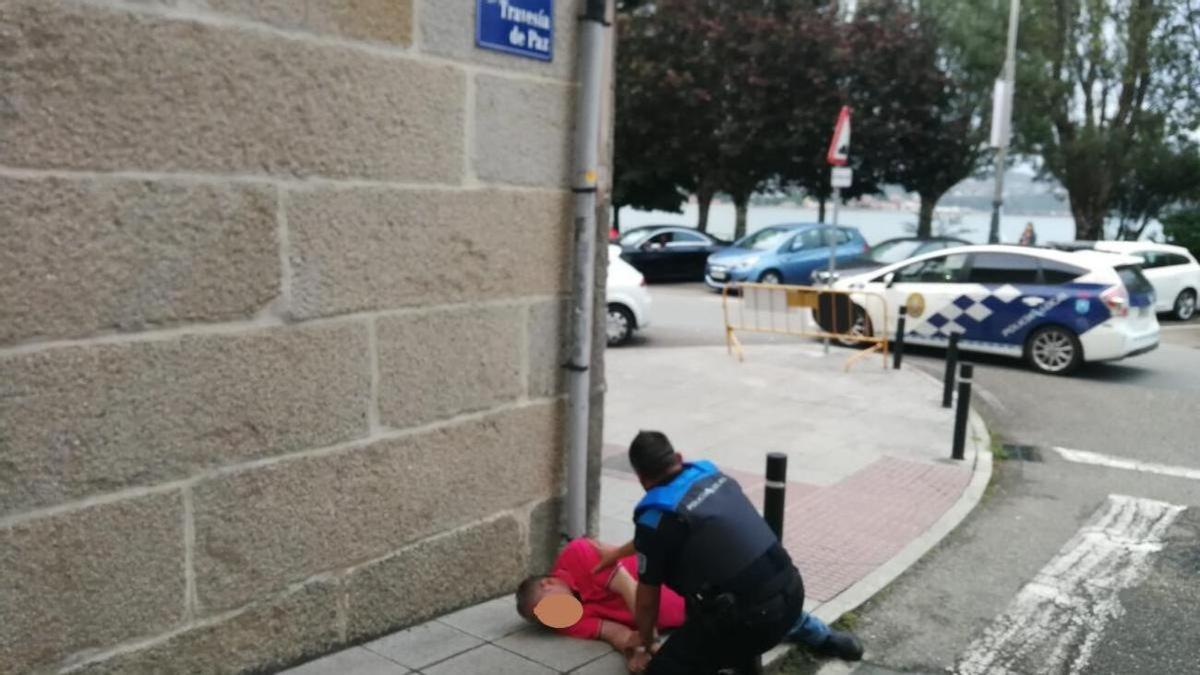 Un agente socorriendo a un hombre en el suelo en una imagen de archivo