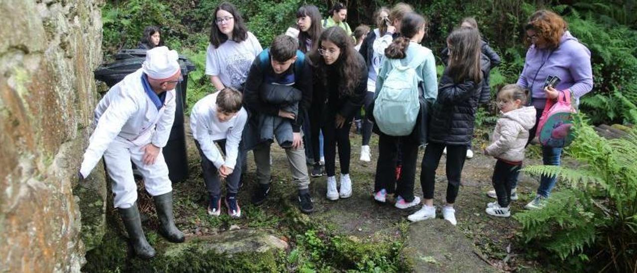 Un integrante de la Asociación Cultural Meiro explica a los jóvenes como el agua hace funcionar las partes del molino.