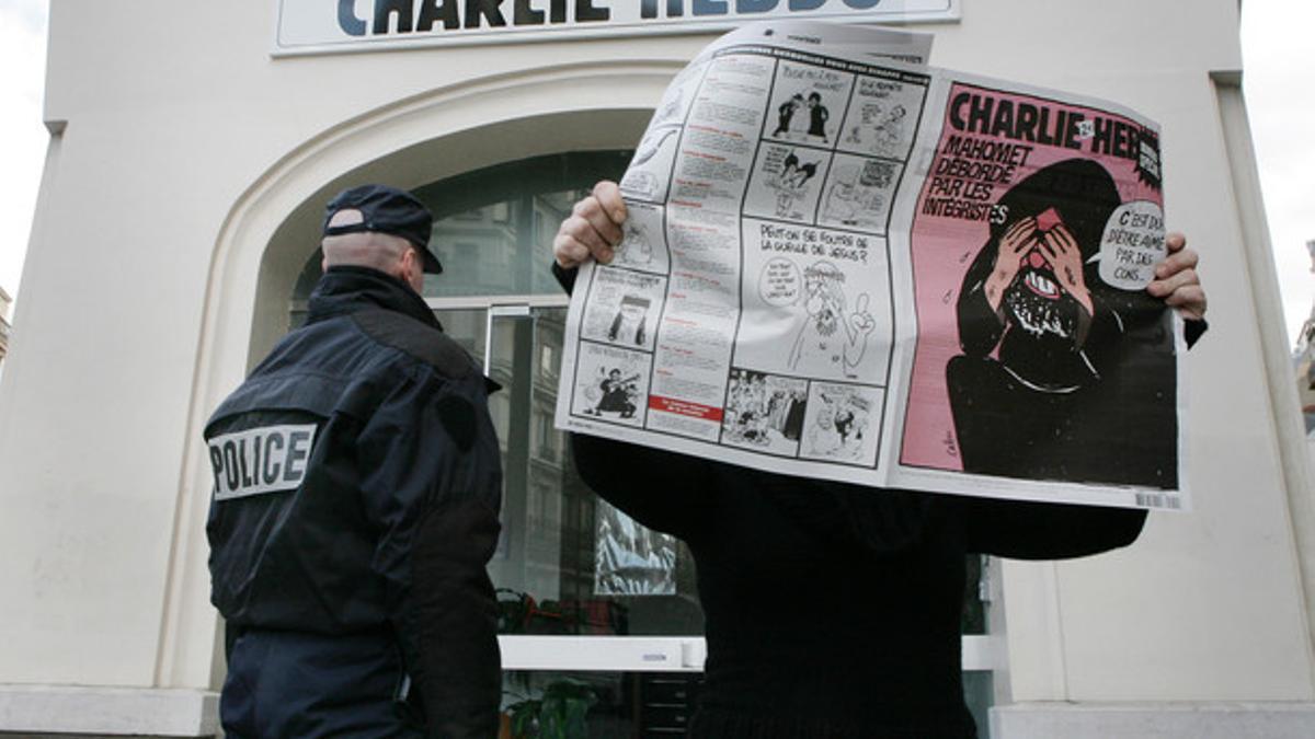 Un lector lee el número de 'Charlie Hebdo' dedicado a las caricaturas de Mahoma ante la sede de la revista, custodiada por la policía, en febrero del 2006.