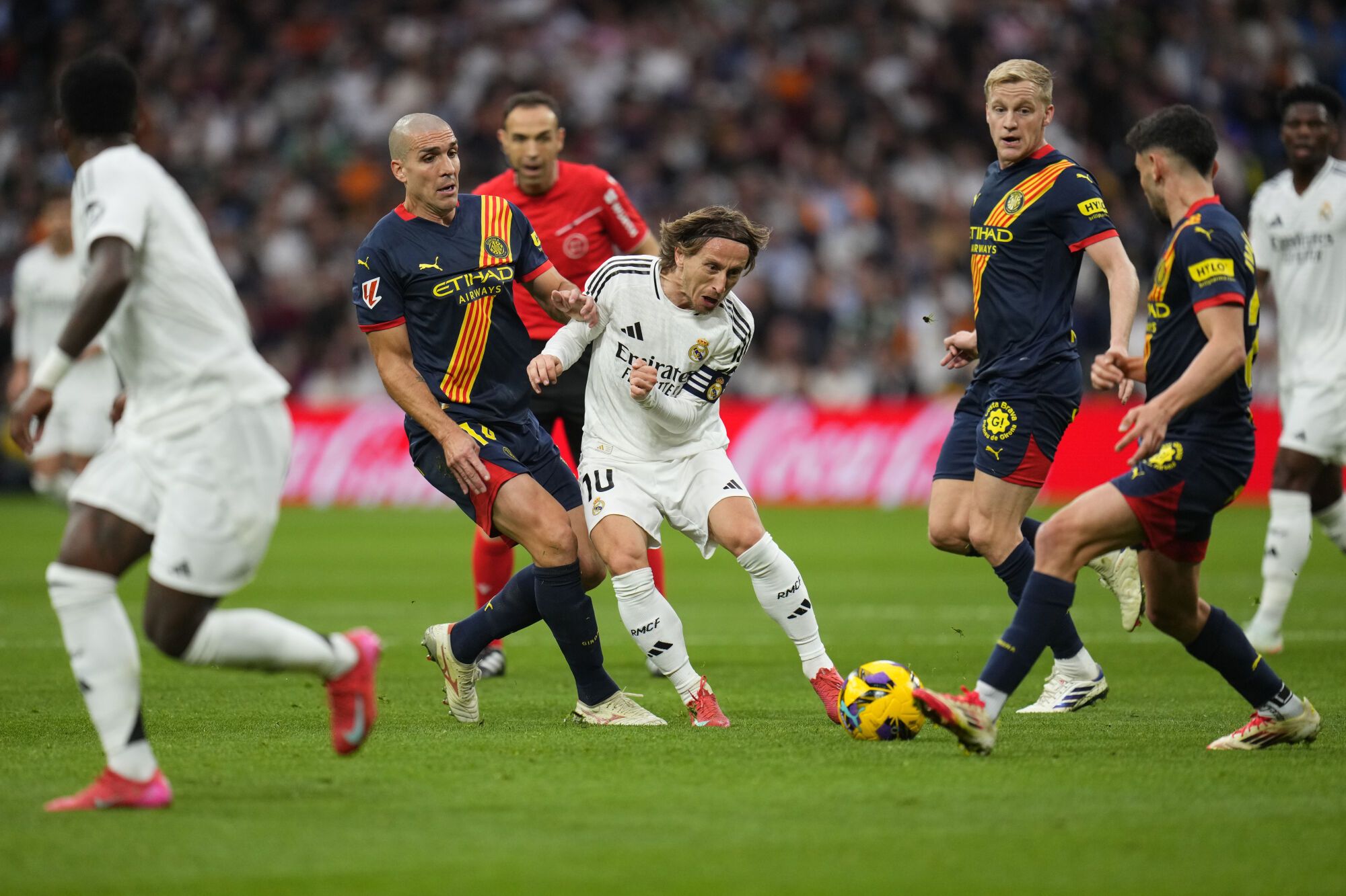 Real Madrid's Luka Modric, centre, and Girona's Oriol Romeu, centre left, challenge for the ball during the Spanish La Liga soccer match between Real Madrid and Girona at the Santiago Bernabeu stadium in Madrid, Spain, Sunday, Feb. 23, 2025. (AP Photo/Manu Fernandez)