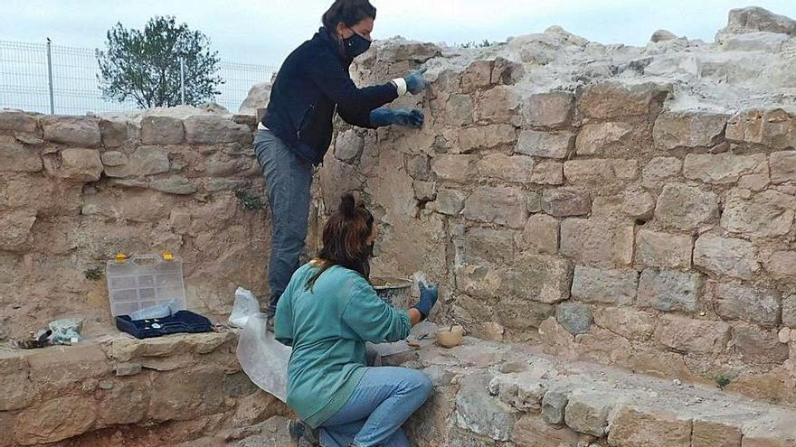 Zaira Bordoy i Sandra Caballero consolidant un arrebossat i al costat hi ha la tomba de la capella excavada a l’argila  | G.C.