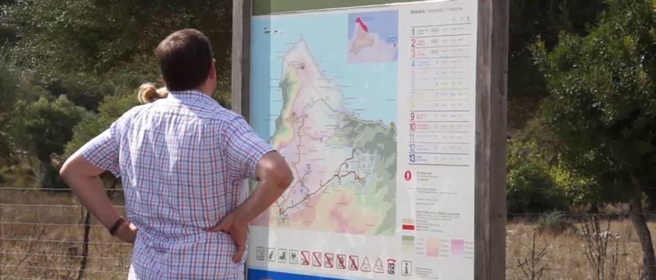 Visitantes del Parc natural de la Península de Llevant ante un cartel explicativo.