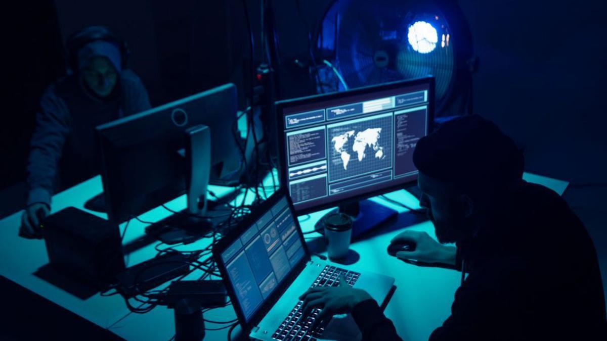 Imaxe de dúas persoas simulando hackear uns ordenadores. 123RF